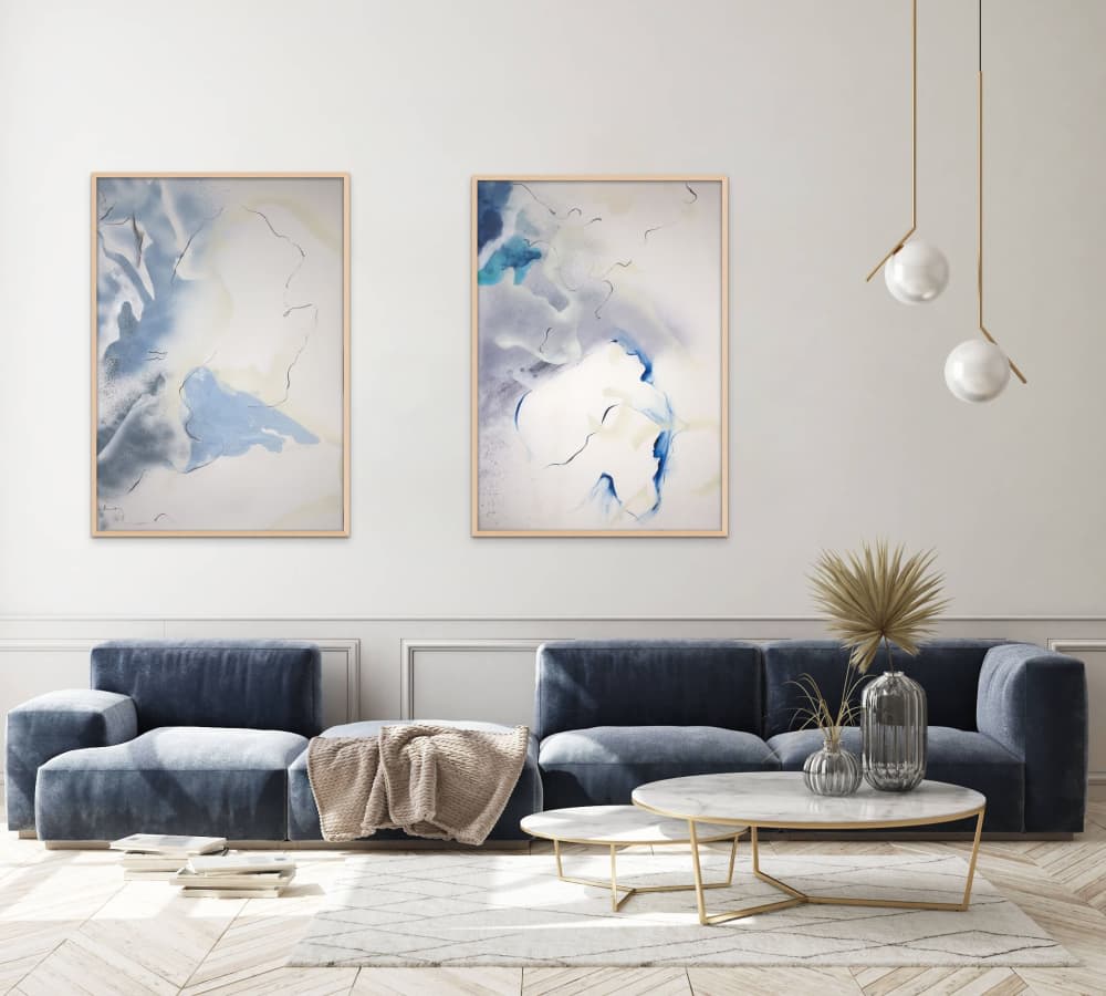 Two abstract, white, blue, and gray paintings framed and hung up on living room wall.