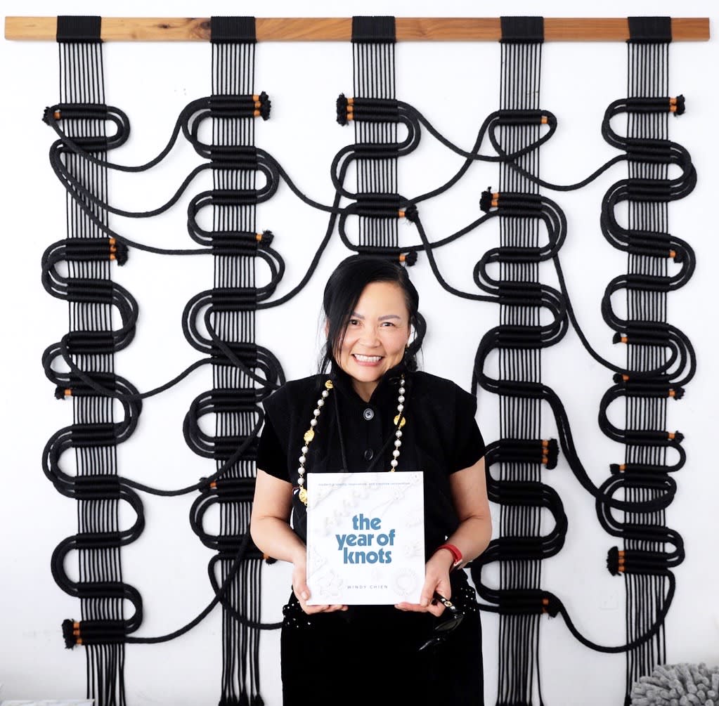 Windy Chien with her new book, "The Year of Knots," in front of her Piece, "Circuit Board" in Wescover's Gallery at West Coast Craft as seen on Wescover.