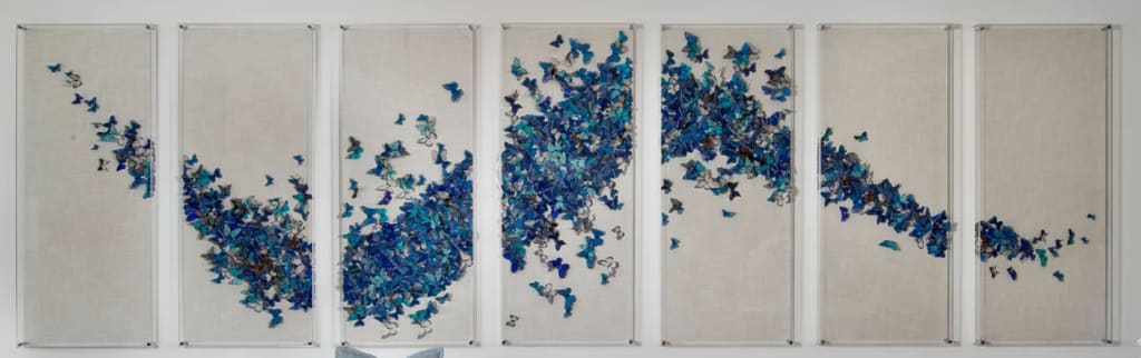 Blue butterflies flying across seven canvases