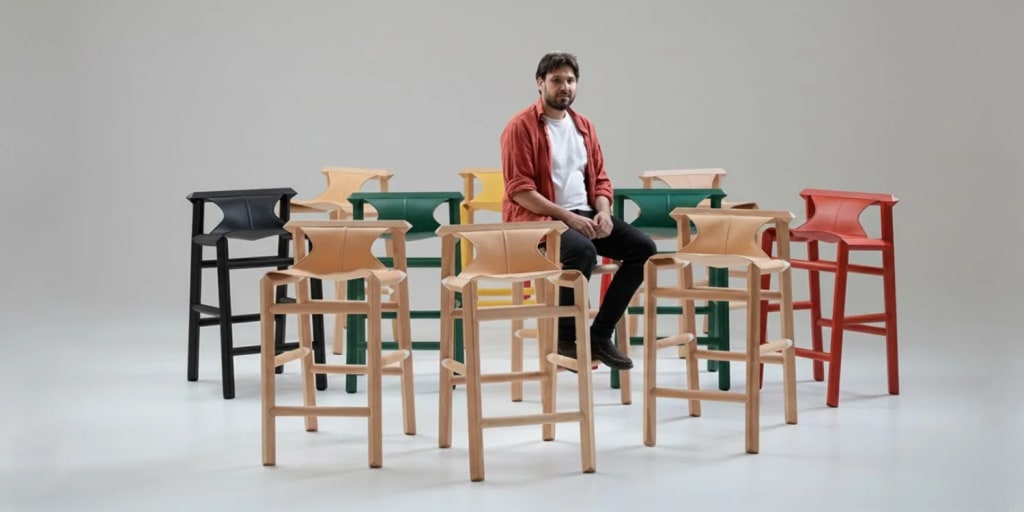 Marcelo of Espina Corona surrounded by a large series of custom wood chairs, demonstrating hospitality-grade production capacity.