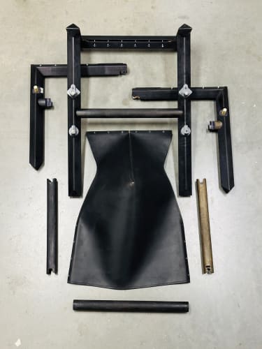Disassembled 1901 chair in black wood showing custom joinery components and high-end leather.
