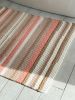 Knitted area rug with white, peach, beige, and gold stripes | Small Rug in Rugs by Anzy Home. Item made of cotton with fiber
