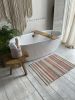 Knitted area rug with white, peach, beige, and gold stripes | Small Rug in Rugs by Anzy Home. Item made of cotton with fiber